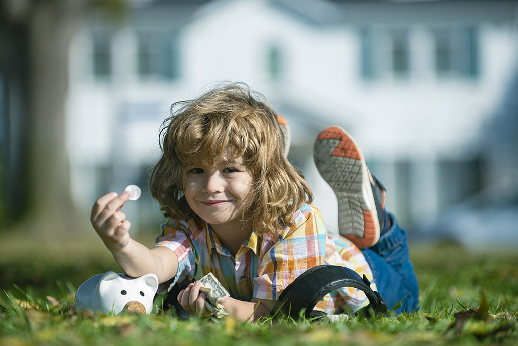 child in grass with piggy bank