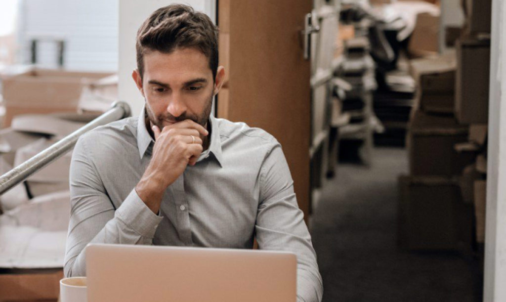 This image depicts a business owner sitting at a desk with a laptop.