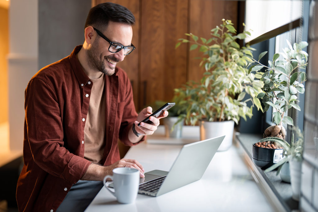 Online Account Opening Secondary a man on phone in front of laptop