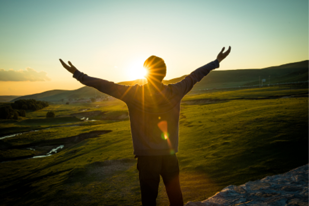 freedom man with arms in air looking at sunset
